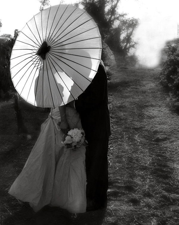 black and white photo - the silhouette of the bride and groom kissing behind a parasol - photo by North Carolina based wedding photographers Cunningham Photo Artists